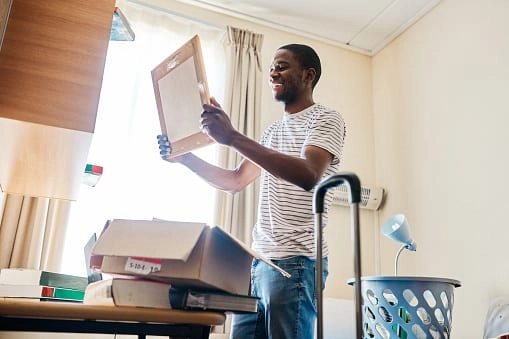 Cropped shot of a cheerful young man unpacking his stuff after arriving at his new home inside during the day